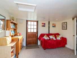 A living room with a wooden door a red covered sofa and wooden cabinets at Shed Your Blues in Brilley near Kington
