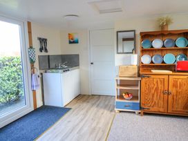 A kitchen area with a sink stove unit a wooden cabinet with plates on display and a small shelf with fruit at Shed Your Blues in Brilley near Kington