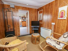 A small sitting room with wicker chairs a small round table a television and wood panelled walls at Shed Your Blues in Brilley near Kington