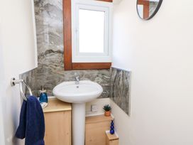 A small bathroom with a pedestal sink a window above and a wooden cabinet next to it at Shed Your Blues Brilley near Kington