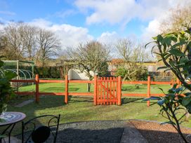 A garden with a wooden fence and gate and a small table with chairs at Shed Your Blues in Brilley near Kington