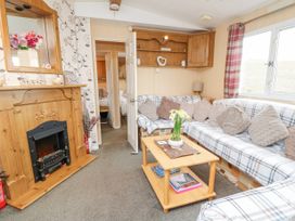 A living room with a wooden fireplace a checkered sofa with cushions a wooden coffee table and a doorway to a bedroom at The Retreat Near Shorwell