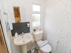A bathroom with a sink a toilet a towel on a rack and a window at The Retreat Near Shorwell