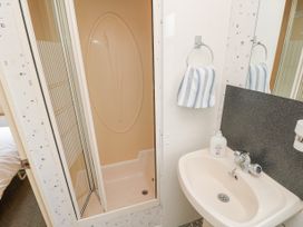 A bathroom with a shower, sink, striped towel, and soap bottle at The Retreat Near Shorwell