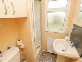 A small bathroom with a sink a toilet a shower cubicle and a window at The Retreat Near Shorwell