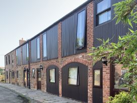 An exterior view of a brick building with multiple windows and doorways at Millers Cottage Seaville near Wigton