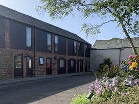 An outdoor area with a building and flowers at Millers Cottage in Seaville near Wigton