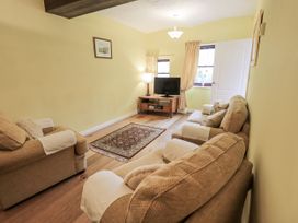 A living room with a sofa, television, and rug at Millers Cottage in Seaville near Wigton