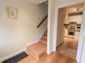 A hallway with a staircase and a view into the kitchen at Millers Cottage Seaville near Wigton