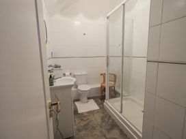A bathroom with a shower, sink, toilet, and chair at Millers Cottage Seaville near Wigton
