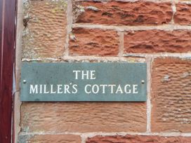 A plaque with the name The Miller's Cottage on a stone wall at Millers Cottage in Seaville near Wigton