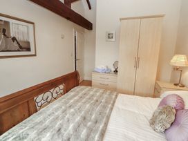 A bedroom with a bed and wardrobe at Millers Cottage in Seaville near Wigton