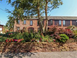 A flower bed and trees outside a brick building at Millers Cottage in Seaville near Wigton