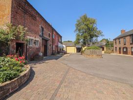 An outdoor area with buildings, pathway, and landscaping at Millers Cottage Seaville near Wigton