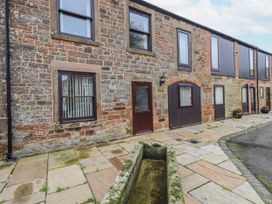 An outdoor view of a stone building with windows and a door at The Coach House near Wigton