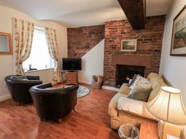 A living room with a fireplace and furniture at The Coach House near Wigton