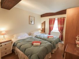 A bedroom with two beds and a lamp at The Coach House near Wigton