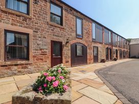 An outdoor area with a flowerbed and a building at The Coach House near Wigton
