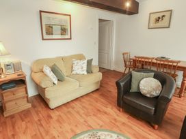 A living room with a sofa, lamp, and dining table at The Coach House near Wigton