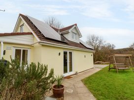 A house with solar panels on the roof and a wooden swing in the garden at Hideaway in Great Torrington
