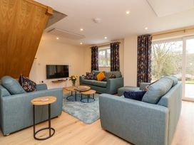 A living room with blue sofas a wall mounted TV round wooden tables and floral curtains at Hideaway in Great Torrington