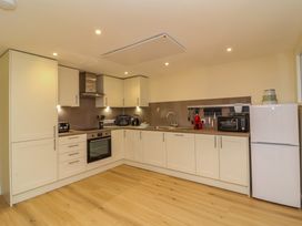 A kitchen with white cabinets a stainless steel oven a white fridge and wooden floor at Hideaway in Great Torrington