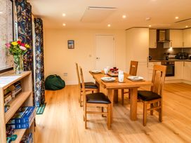 A dining area with a wooden table set for four and a kitchen with white cabinets at Hideaway in Great Torrington