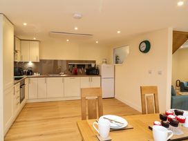 A kitchen with white cabinets wooden floor dining table with cupcakes and mugs at Hideaway in Great Torrington