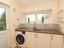 A laundry room with a washing machine sink and two windows with plants on the windowsill at Hideaway in Great Torrington