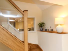 A staircase with a wooden handrail a blue and white plant pot letters spelling relax and a lamp on a ledge at Hideaway in Great Torrington