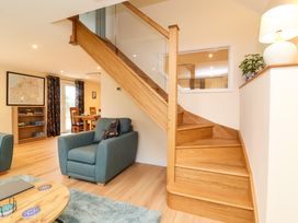 A living area with wooden staircase blue armchairs a dining table and bookshelf at Hideaway in Great Torrington
