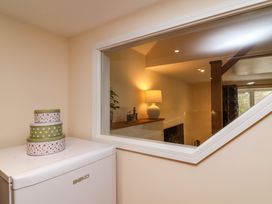 A small white refrigerator with decorative tin boxes on top next to an interior window showing a room with a lamp and wooden railing at Hideaway in Great Torrington