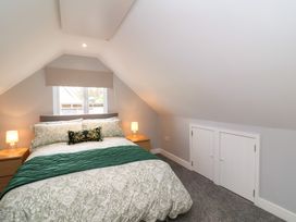A bedroom with a double bed flanked by two bedside tables with lamps and a window behind at Hideaway in Great Torrington