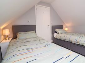 A bedroom with two single beds with striped bed covers and bedside tables with lamps at Hideaway in Great Torrington