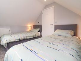 A bedroom with two single beds with striped bedding and a lit bedside lamp at Hideaway in Great Torrington