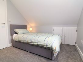 A bedroom with a single bed a bedside lamp and built-in storage behind two small doors at Hideaway in Great Torrington