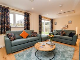 A living room with two sofas a round wooden coffee table and patterned curtains at Hideaway in Great Torrington