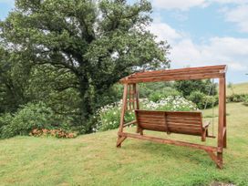 A swing in a garden with trees and flowers at Hideaway in Great Torrington