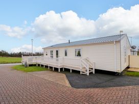 A single-story mobile home with ramp and stairs on a paved and grassy plot at Beech 20 in Cayton Bay