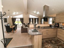 An open plan kitchen with wooden cabinets and a dining area with a wooden table and black chairs at Beech 20 in Cayton Bay