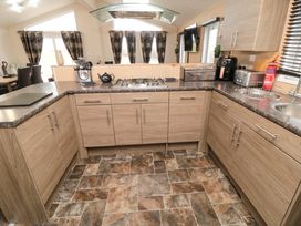 A kitchen with wooden cabinets a gas stove a sink toaster and air fryer at Beech 20 in Cayton Bay