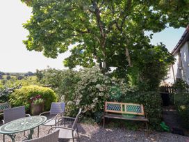 A garden with a table and chairs under a tree at Magnolia View in Goodleigh near Barnstaple