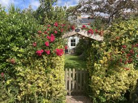 A garden entrance with flowers and a wooden gate at 5 Bed Cottage Mumbles
