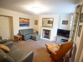 A living room with sofas, a television and wall art at 5 Bed Cottage Mumbles