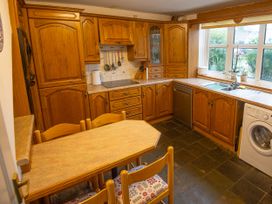 A kitchen with wooden cabinets, table and chairs at 5 Bed Cottage Mumbles