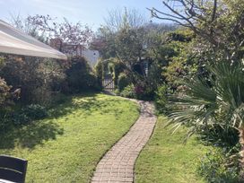 A garden with a pathway leading to a gate at 5 Bed Cottage Mumbles