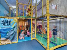 An indoor play area with a play structure and children playing at Windsurfer’s Rest - Hayling Island