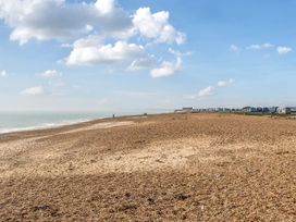 A beach with huts and people walking at Windsurfer’s Rest - Hayling Island