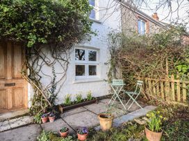 A small outdoor patio with a wooden door white window green plants and two light green metal chairs and a table at Briar Orchard Annex in Ammerham near Winsham