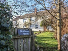 A garden path leading to a white house with wooden door and windows behind a wooden gate with a sign reading Briar Orchard Annexe at Briar Orchard Annex in Ammerham near Winsham